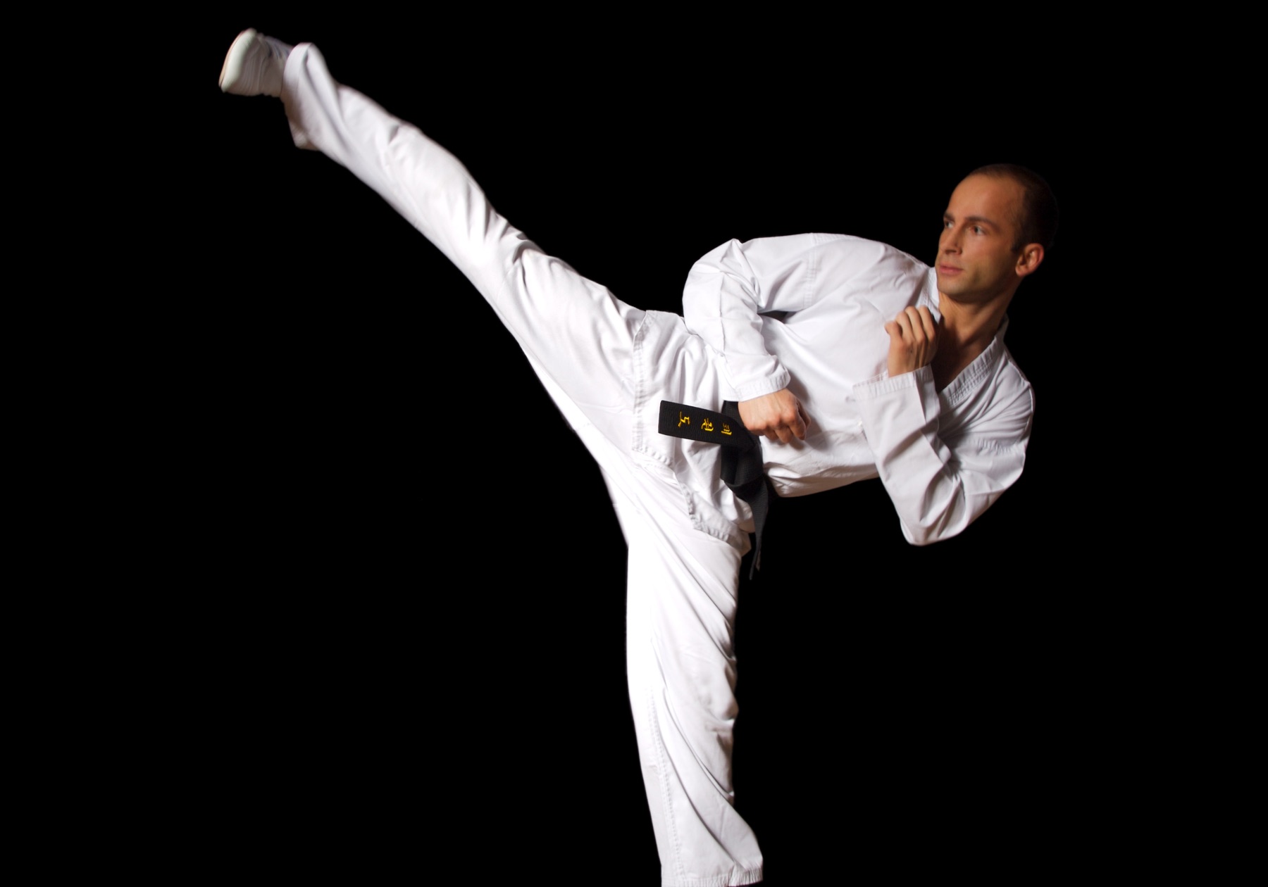 Telat bei einem Taekwondo-Highkick im weißen Dobok mit Schwarzgurt